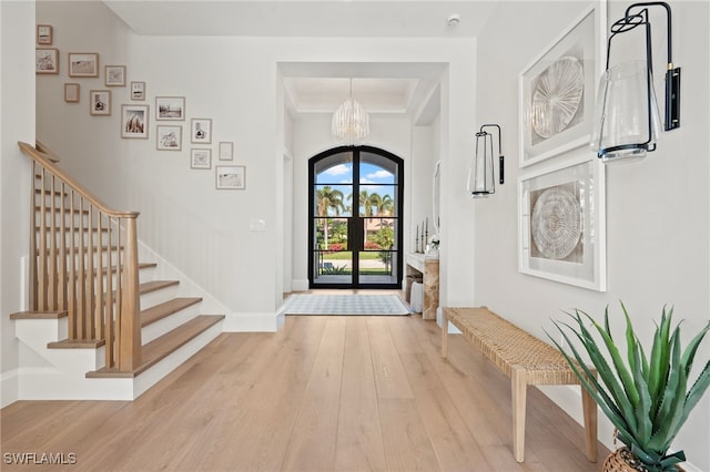 entrance foyer featuring light hardwood / wood-style floors, french doors, and a chandelier