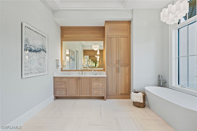 bathroom with an inviting chandelier, vanity, and a tub