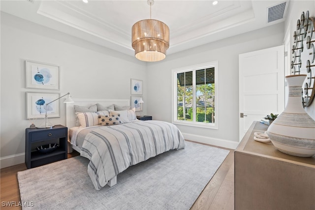 bedroom with a tray ceiling and light hardwood / wood-style floors