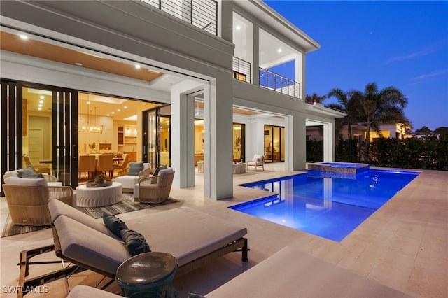 pool at dusk with a patio and an in ground hot tub