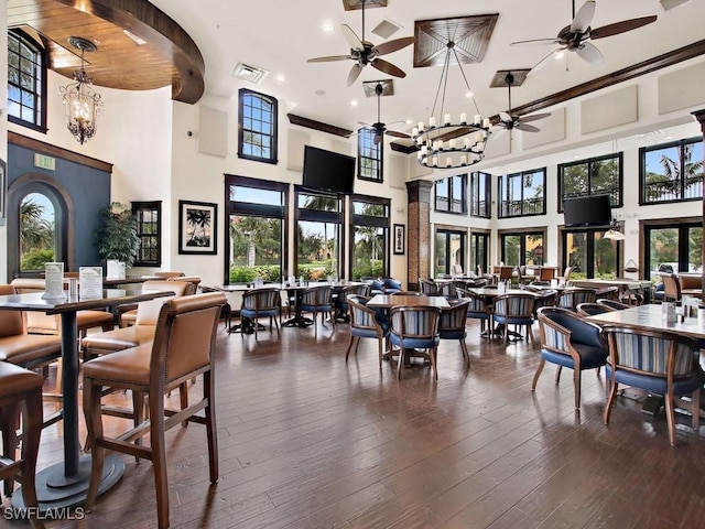 dining room with a healthy amount of sunlight, a towering ceiling, dark hardwood / wood-style flooring, and an inviting chandelier