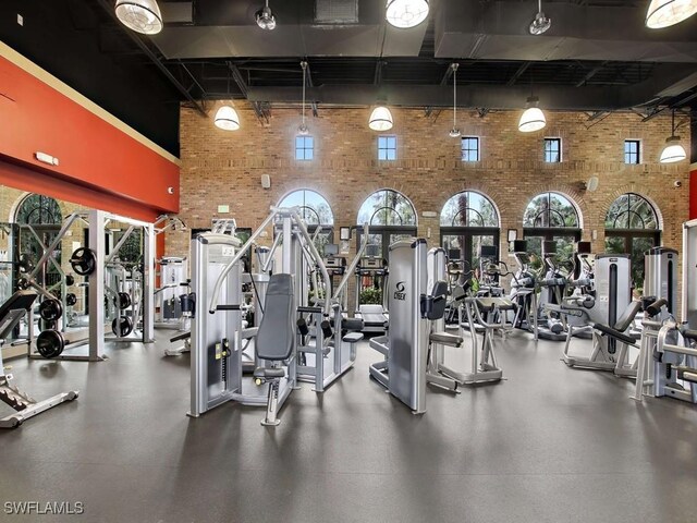 workout area featuring a high ceiling and brick wall