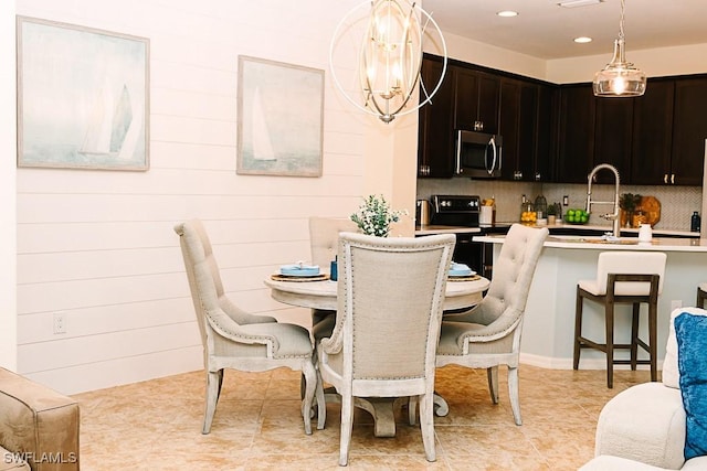 dining area with an inviting chandelier, light tile patterned flooring, wood walls, and sink