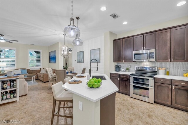 kitchen featuring pendant lighting, sink, a kitchen breakfast bar, stainless steel appliances, and a center island with sink