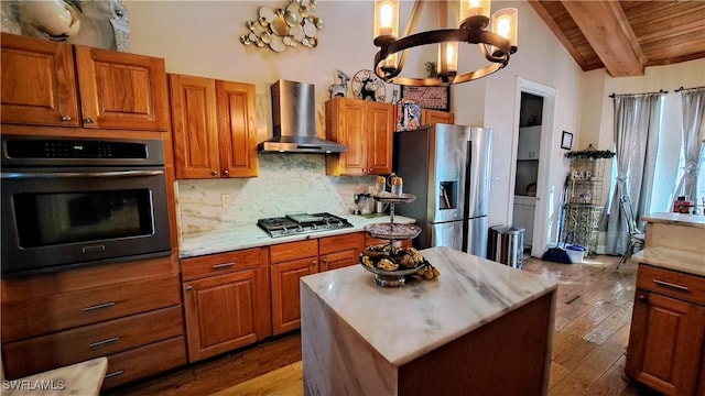 kitchen featuring a center island, a chandelier, backsplash, stainless steel appliances, and wall chimney exhaust hood