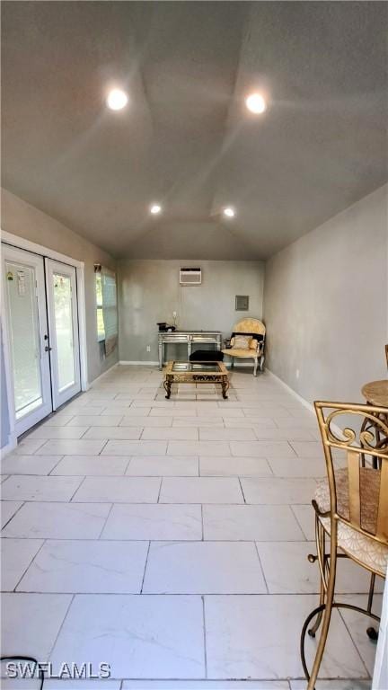 unfurnished dining area featuring a wall mounted air conditioner, french doors, and lofted ceiling