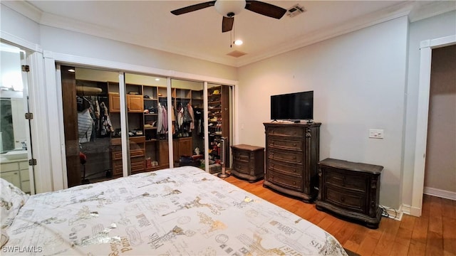 bedroom with hardwood / wood-style floors, ensuite bath, a closet, ornamental molding, and ceiling fan