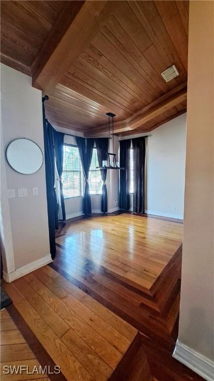 unfurnished dining area with beam ceiling, wooden ceiling, and wood-type flooring