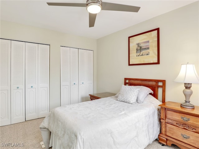 carpeted bedroom featuring two closets and ceiling fan