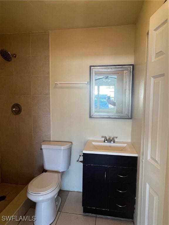 bathroom featuring tiled shower, vanity, tile patterned floors, and toilet