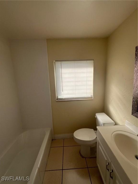 bathroom with tile patterned flooring, vanity, a bath, and toilet