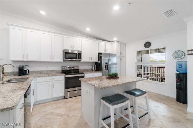 kitchen with white cabinets, appliances with stainless steel finishes, a center island, and sink