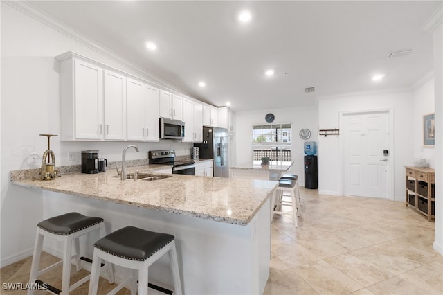 kitchen with a breakfast bar, white cabinets, sink, appliances with stainless steel finishes, and kitchen peninsula