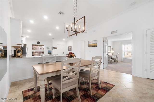 dining room with crown molding, light colored carpet, and a notable chandelier