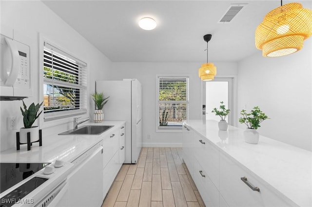 kitchen featuring hanging light fixtures, sink, and white cabinets