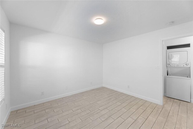 2722 Arbutus St Unit C2, Naples, FL 34112 - spare room featuring stacked washer / dryer, light wood-type flooring, baseboards, and a smoke detector