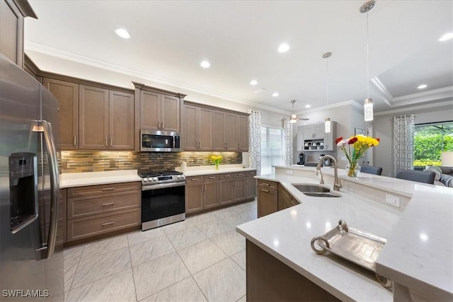 kitchen with ceiling fan, sink, stainless steel appliances, pendant lighting, and ornamental molding