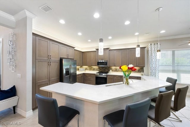 kitchen with ceiling fan, hanging light fixtures, stainless steel appliances, a breakfast bar area, and decorative backsplash