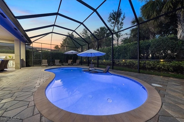 pool at dusk with a patio area and glass enclosure