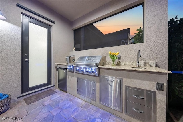 patio terrace at dusk with area for grilling, grilling area, and sink