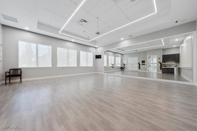 workout area with a tray ceiling and hardwood / wood-style flooring