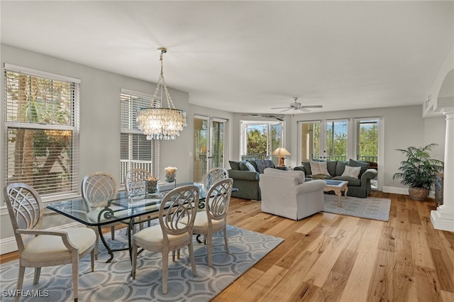 dining area featuring decorative columns, a healthy amount of sunlight, ceiling fan with notable chandelier, and light wood-type flooring