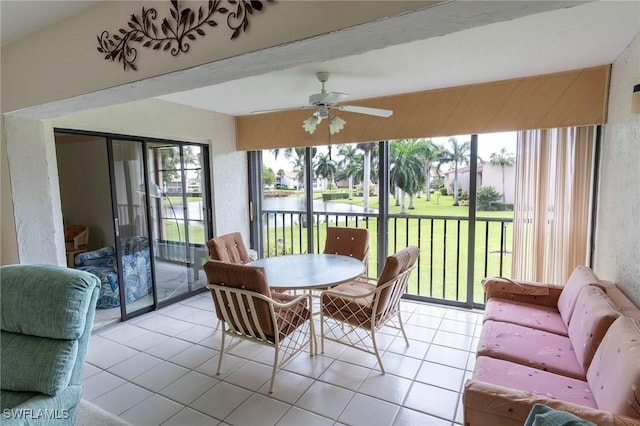 sunroom with ceiling fan and a water view