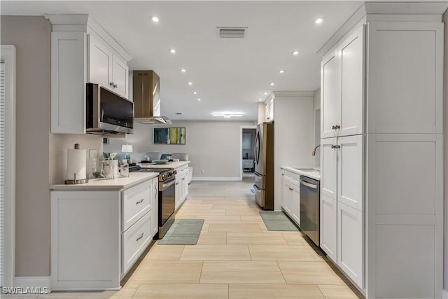 kitchen with white cabinets, wall chimney exhaust hood, sink, and stainless steel appliances