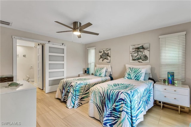 bedroom with ensuite bath, ceiling fan, and a barn door