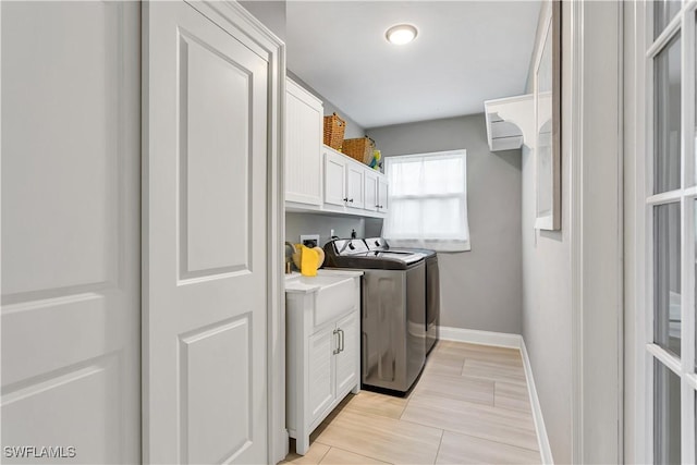 clothes washing area featuring cabinets and independent washer and dryer