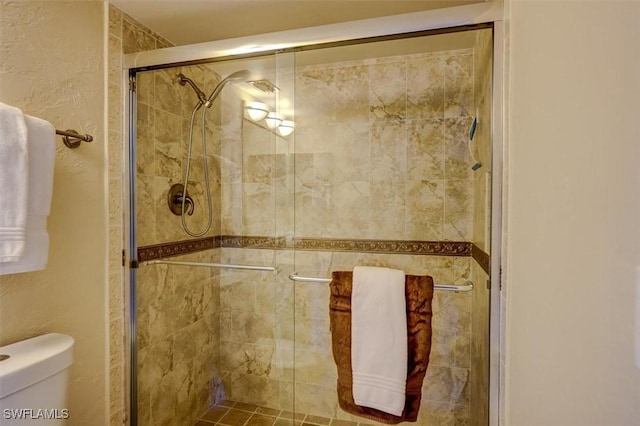 bathroom featuring a shower with door and toilet