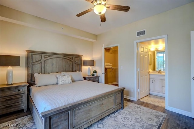 bedroom with ensuite bathroom, a walk in closet, ceiling fan, light wood-type flooring, and a closet