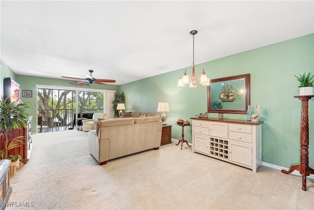 carpeted living room featuring ceiling fan with notable chandelier