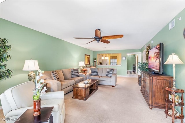 carpeted living room featuring ceiling fan with notable chandelier