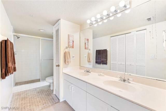 bathroom with walk in shower, tile patterned floors, a textured ceiling, toilet, and vanity