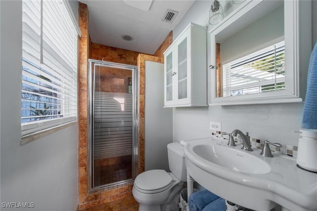 full bathroom with toilet, a stall shower, a sink, and visible vents