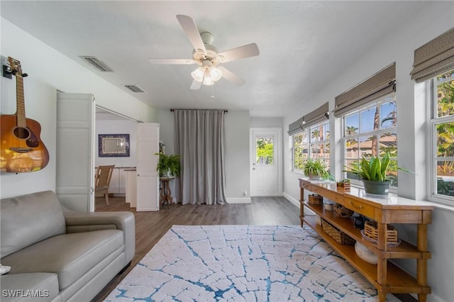 living room with a ceiling fan, baseboards, visible vents, and dark wood-style flooring