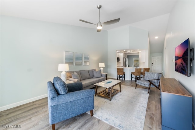 living room featuring hardwood / wood-style flooring, ceiling fan, and high vaulted ceiling