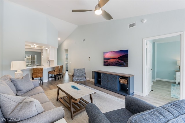 living room featuring ceiling fan, high vaulted ceiling, sink, and light hardwood / wood-style floors