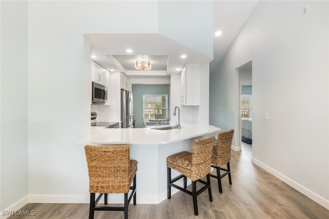 kitchen with sink, a breakfast bar area, white cabinets, kitchen peninsula, and stainless steel appliances