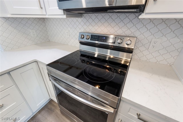 kitchen with electric stove, white cabinetry, dark hardwood / wood-style flooring, and backsplash