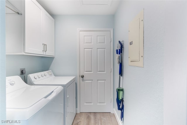 laundry room with cabinets, electric panel, washer and clothes dryer, and light wood-type flooring