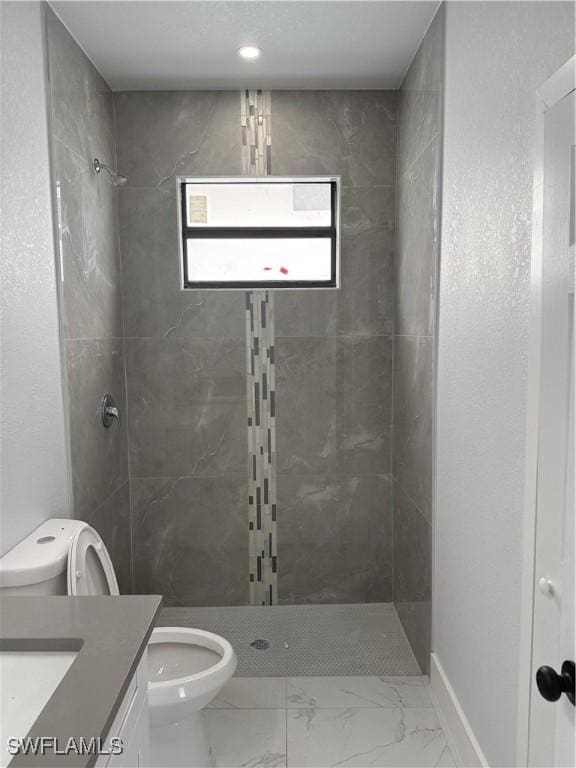 bathroom featuring tiled shower, vanity, and toilet