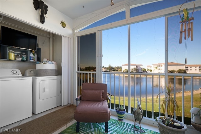 clothes washing area featuring tile patterned flooring, a water view, and washing machine and clothes dryer