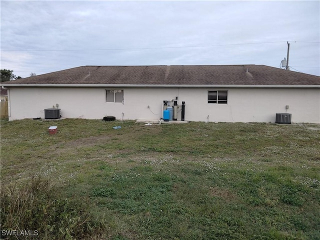 back of property featuring a lawn and central AC