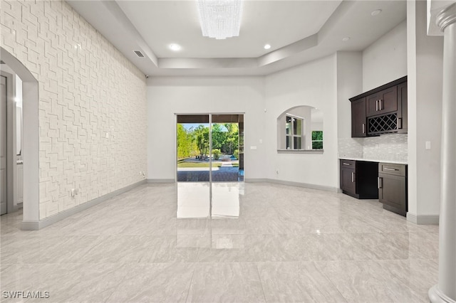 unfurnished living room with a chandelier, a towering ceiling, and a tray ceiling