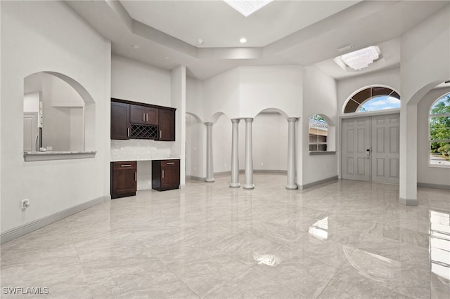 foyer entrance featuring decorative columns and a towering ceiling