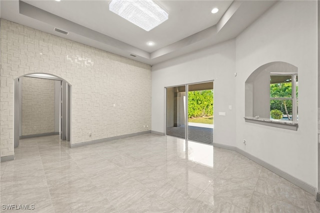 spare room featuring a chandelier, a towering ceiling, and a tray ceiling