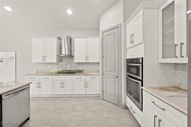 kitchen with white cabinets, light stone countertops, wall chimney exhaust hood, and appliances with stainless steel finishes