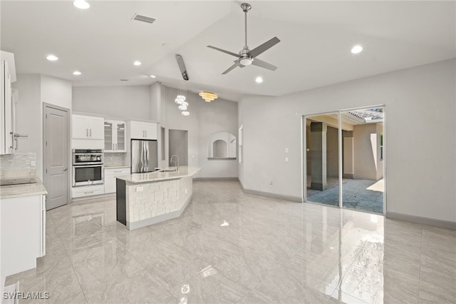 kitchen featuring sink, a kitchen island with sink, decorative backsplash, white cabinets, and appliances with stainless steel finishes